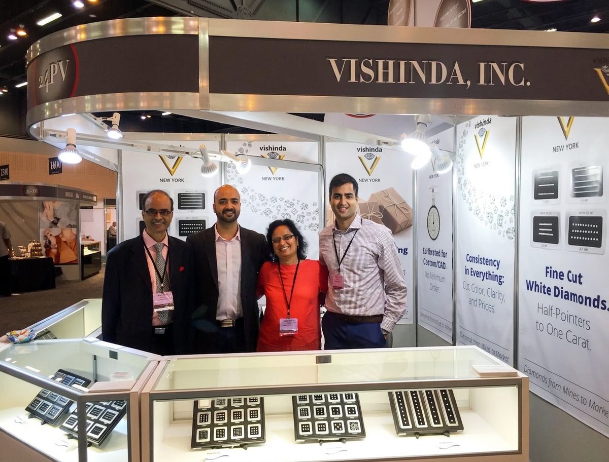 The Vishinda team welcoming visitors at their trade show booth, with displays of calibrated melee diamonds
